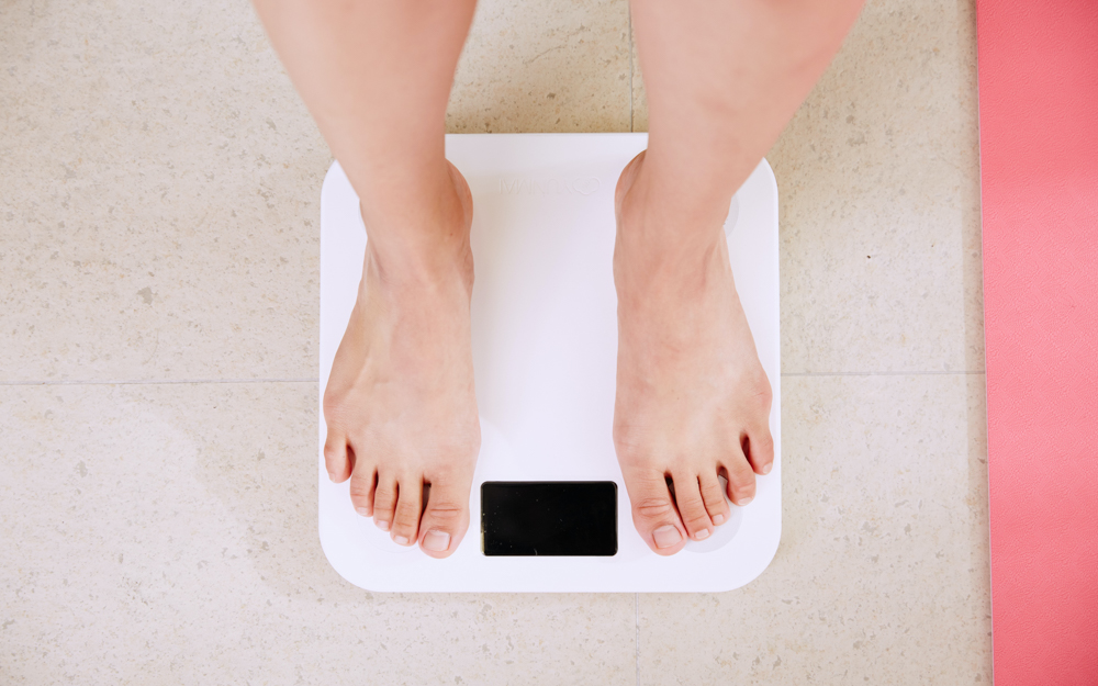 Person standing on scale managing their weight with daily fiber